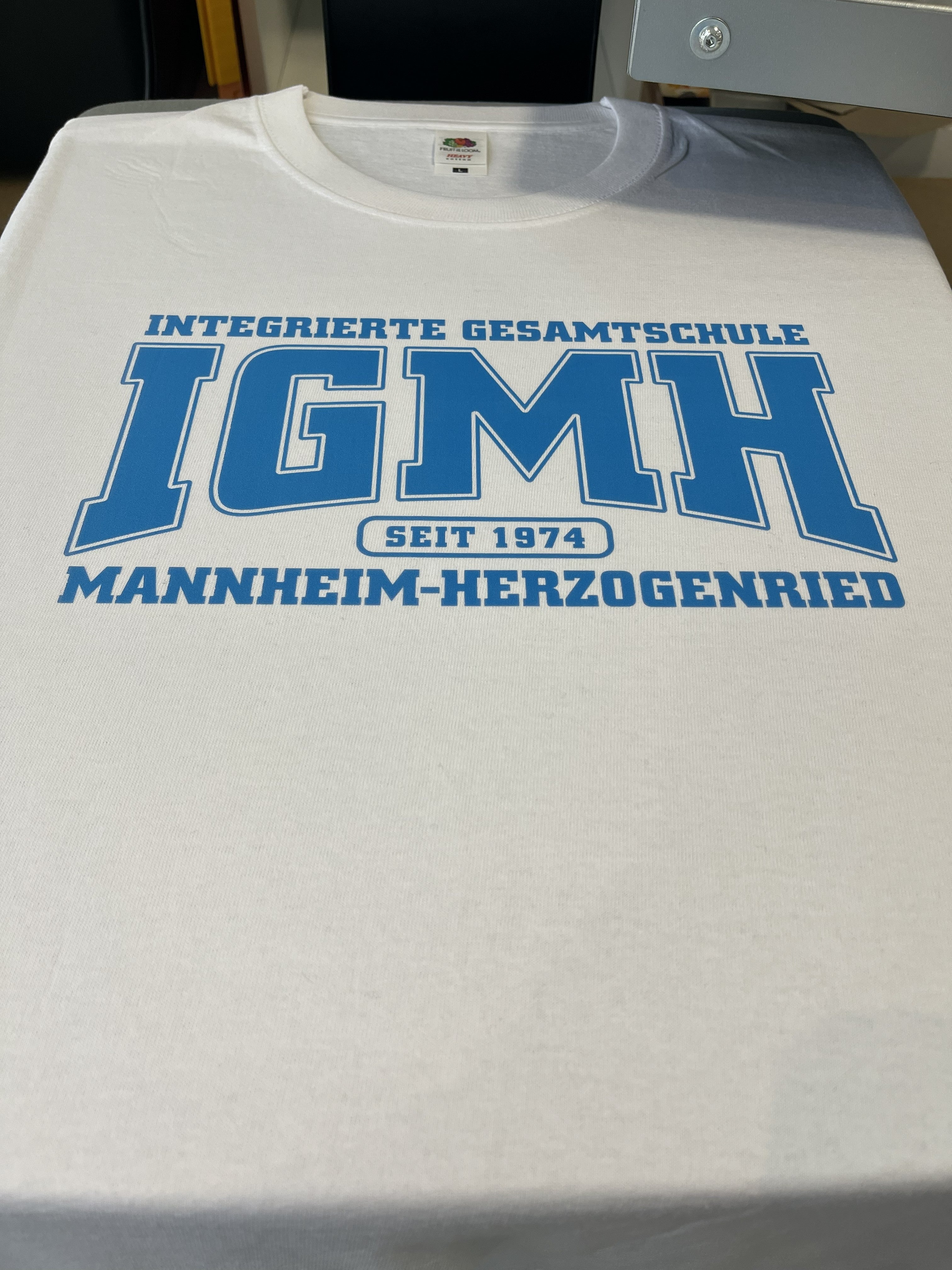 Weißes T-Shirt mit blauem Aufdruck einer Gesamtschule
