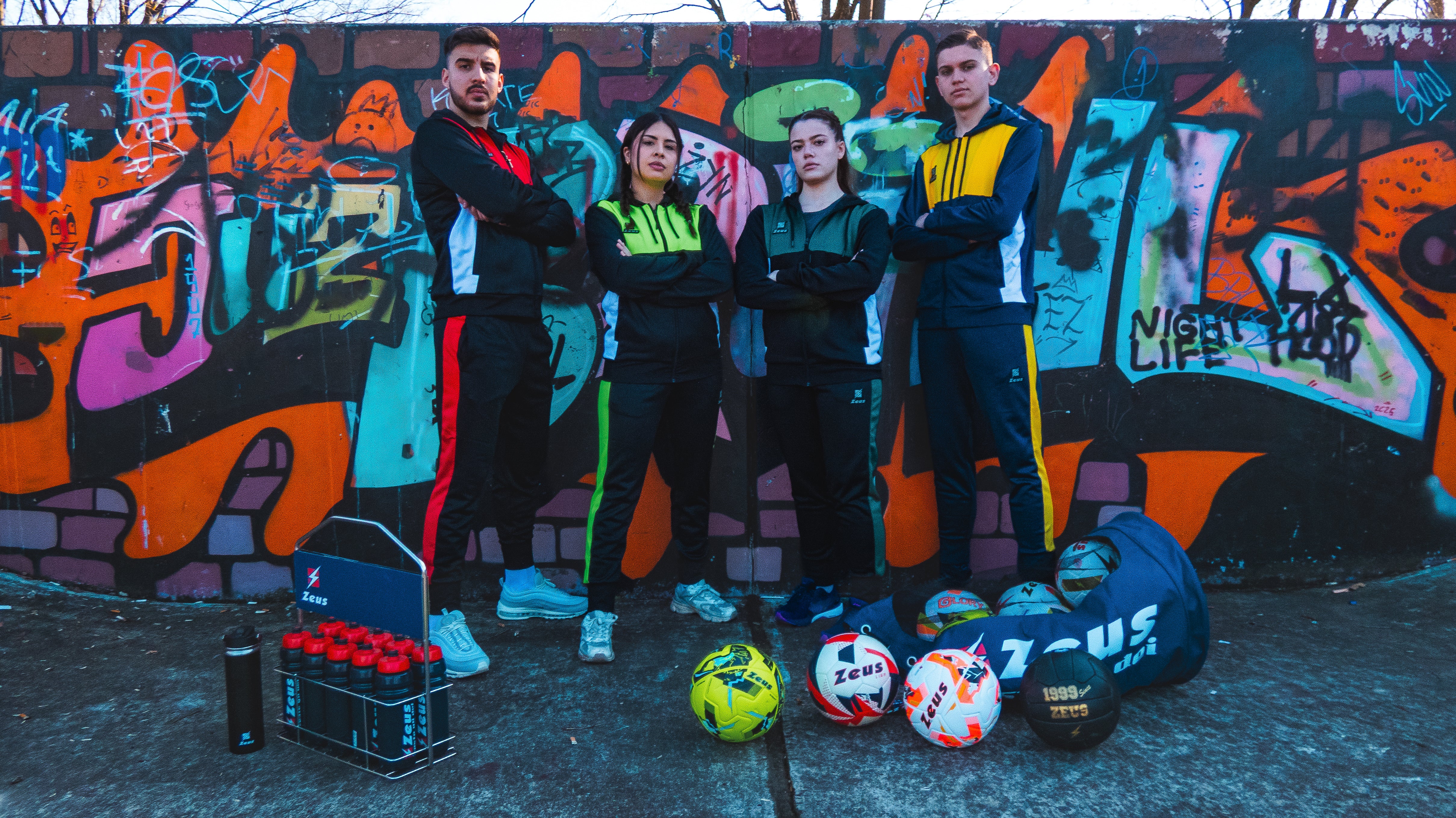 Gruppe von Sportlerinnen und Sportlern in Zeus Teamwear vor einer Graffitiwand