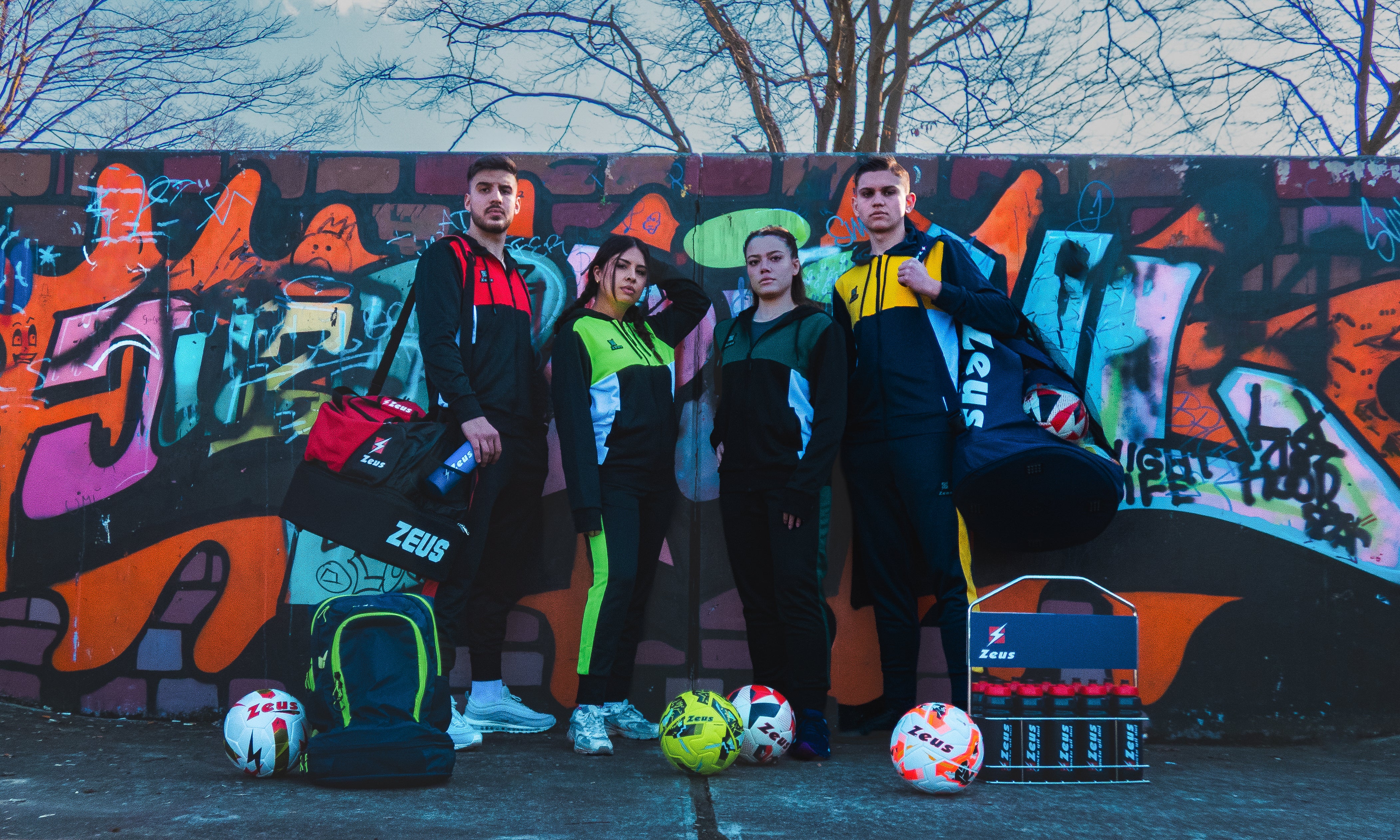 Gruppe von Sportlerinnen und Sportlern in Teamwear vor einer Graffitiwand